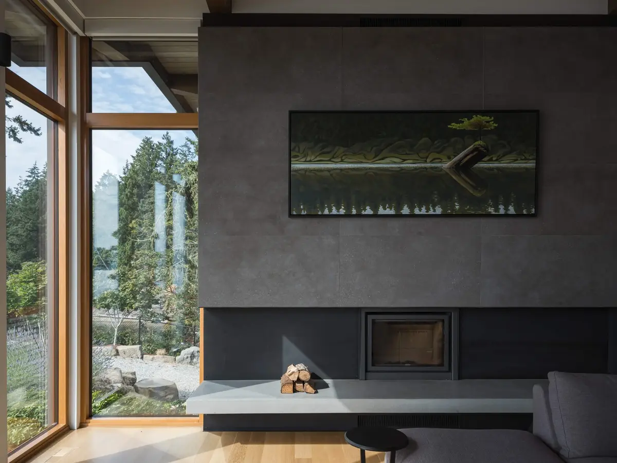 Fireplace of large grey panels with a pale hearth shelf and stacked firewood