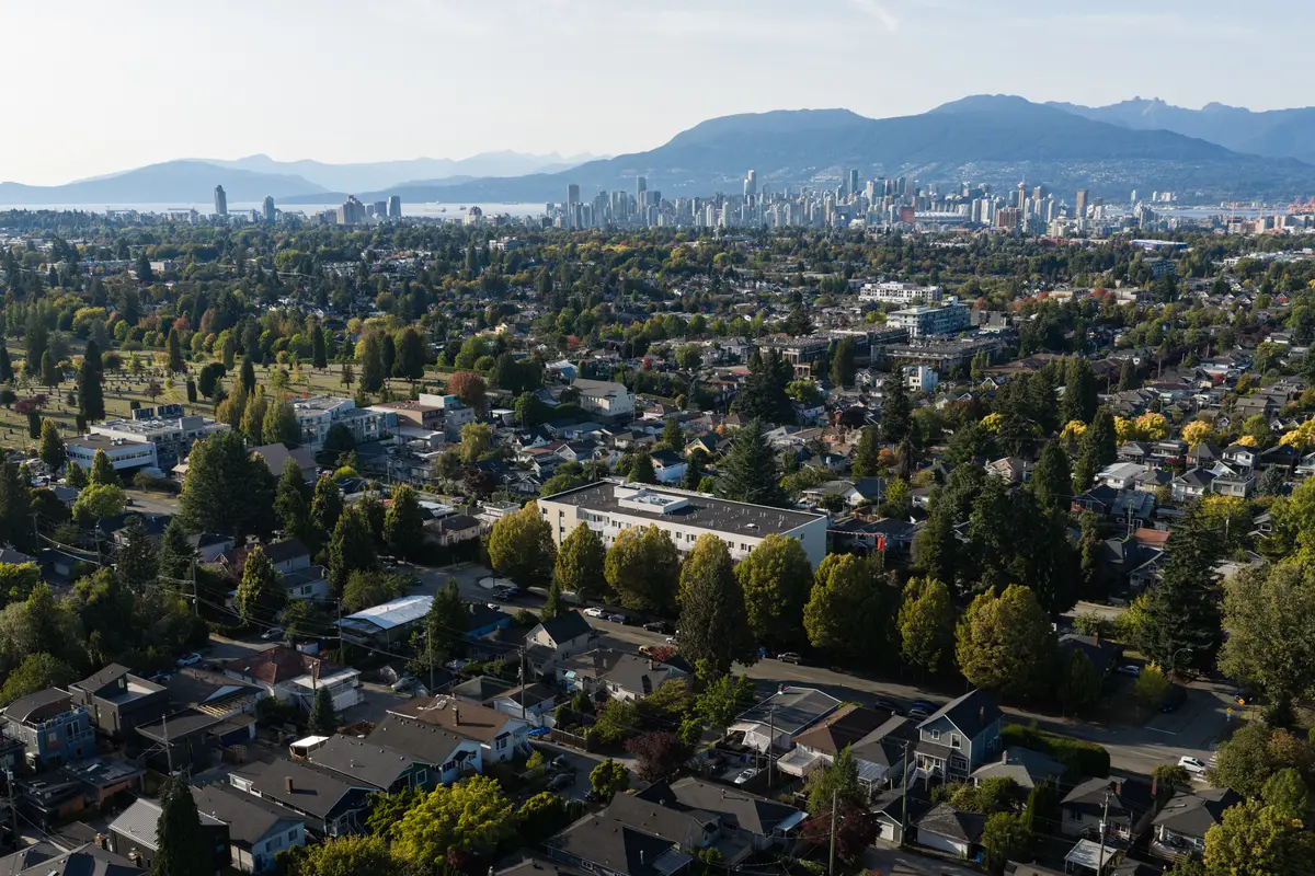 Houses and trees in the foreground, downtown towers and mountains beyond