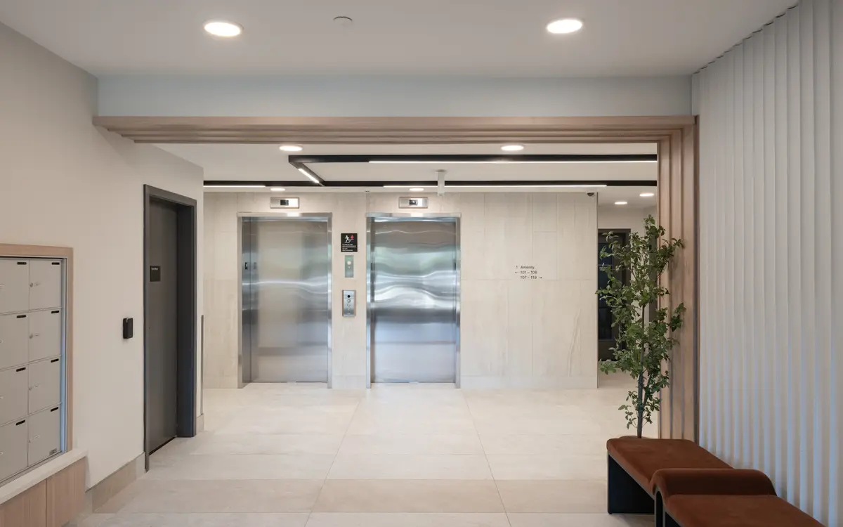 The lobby, two elevators, a bench, and a wood slat wall