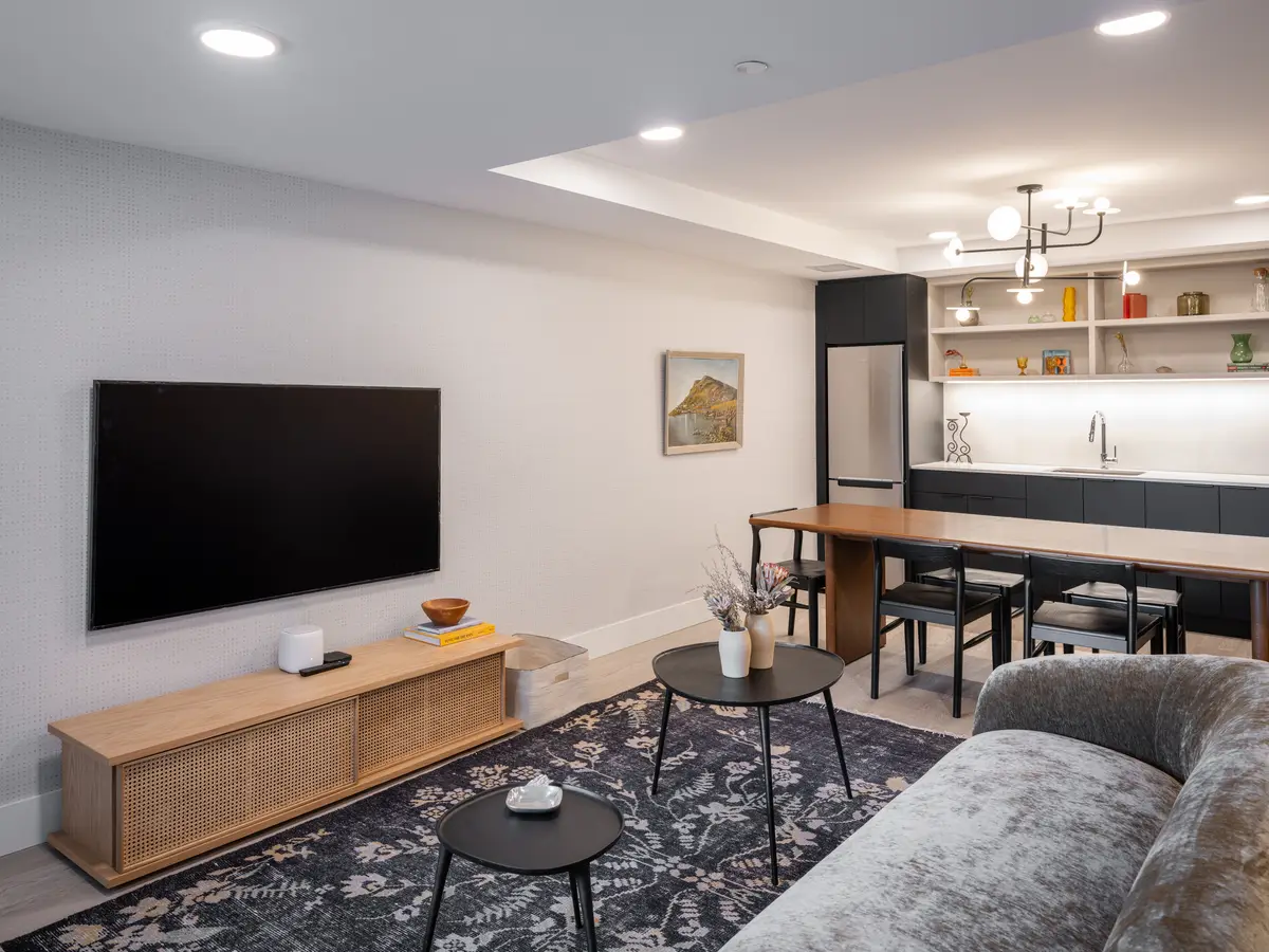 The living room, a sofa facing the television and the kitchen behind