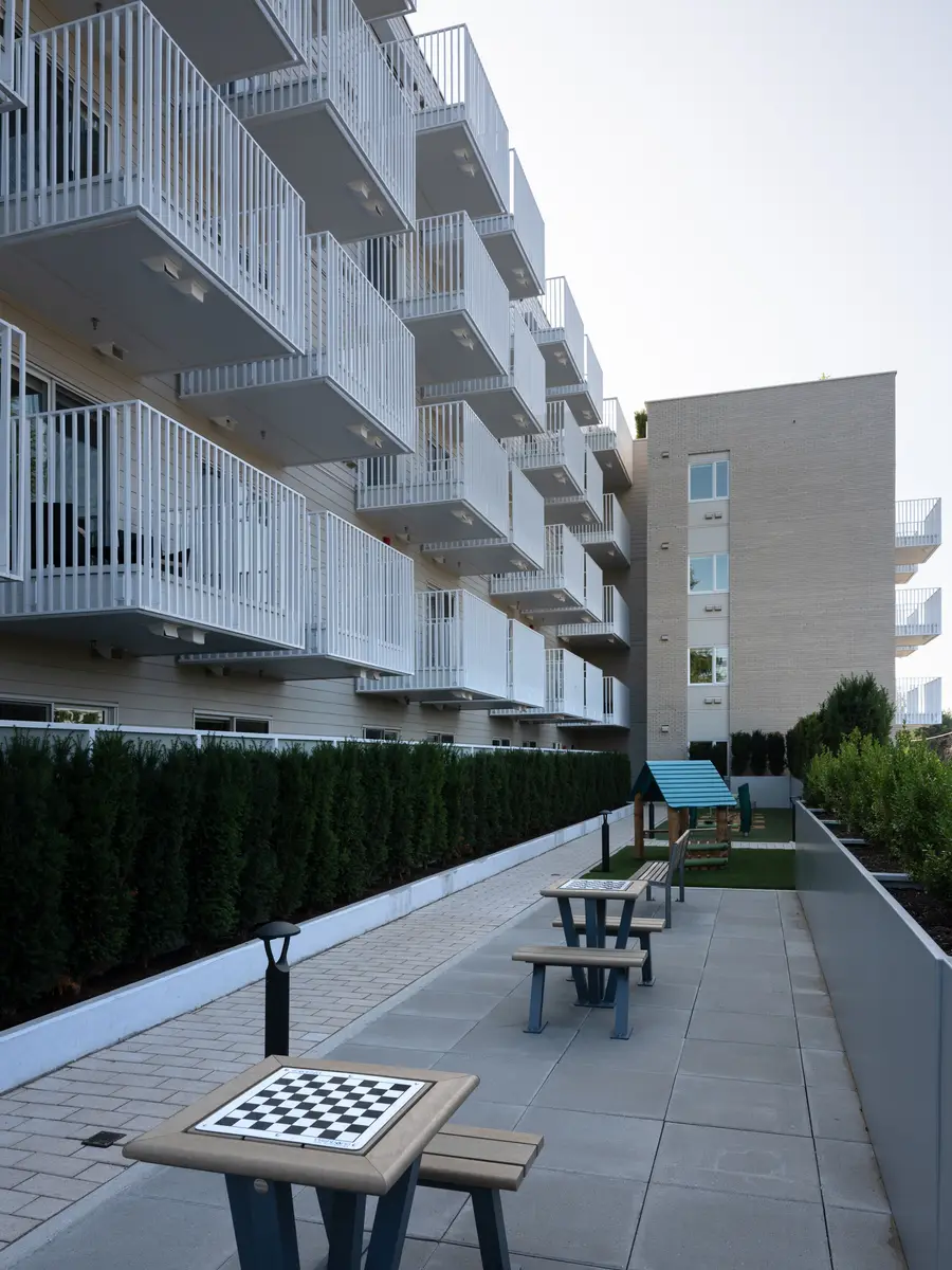 An outdoor walkway along the building, a picnic table and a chessboard