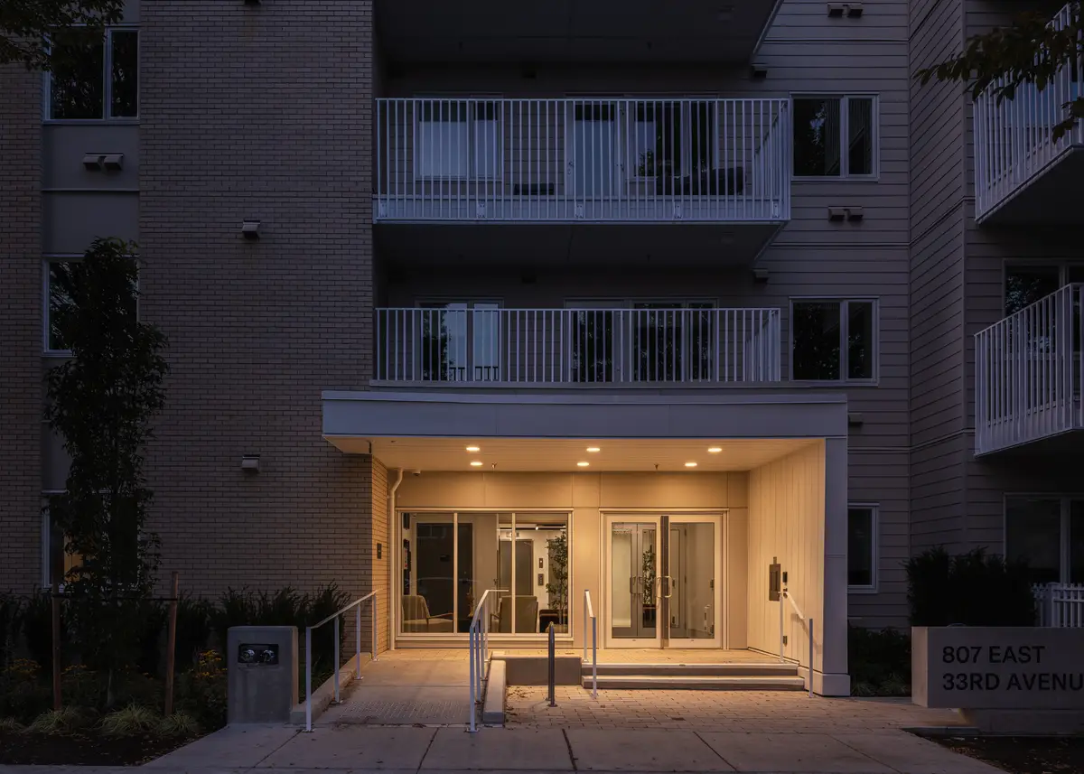 The entry lit at dusk, glass doors under the canopy