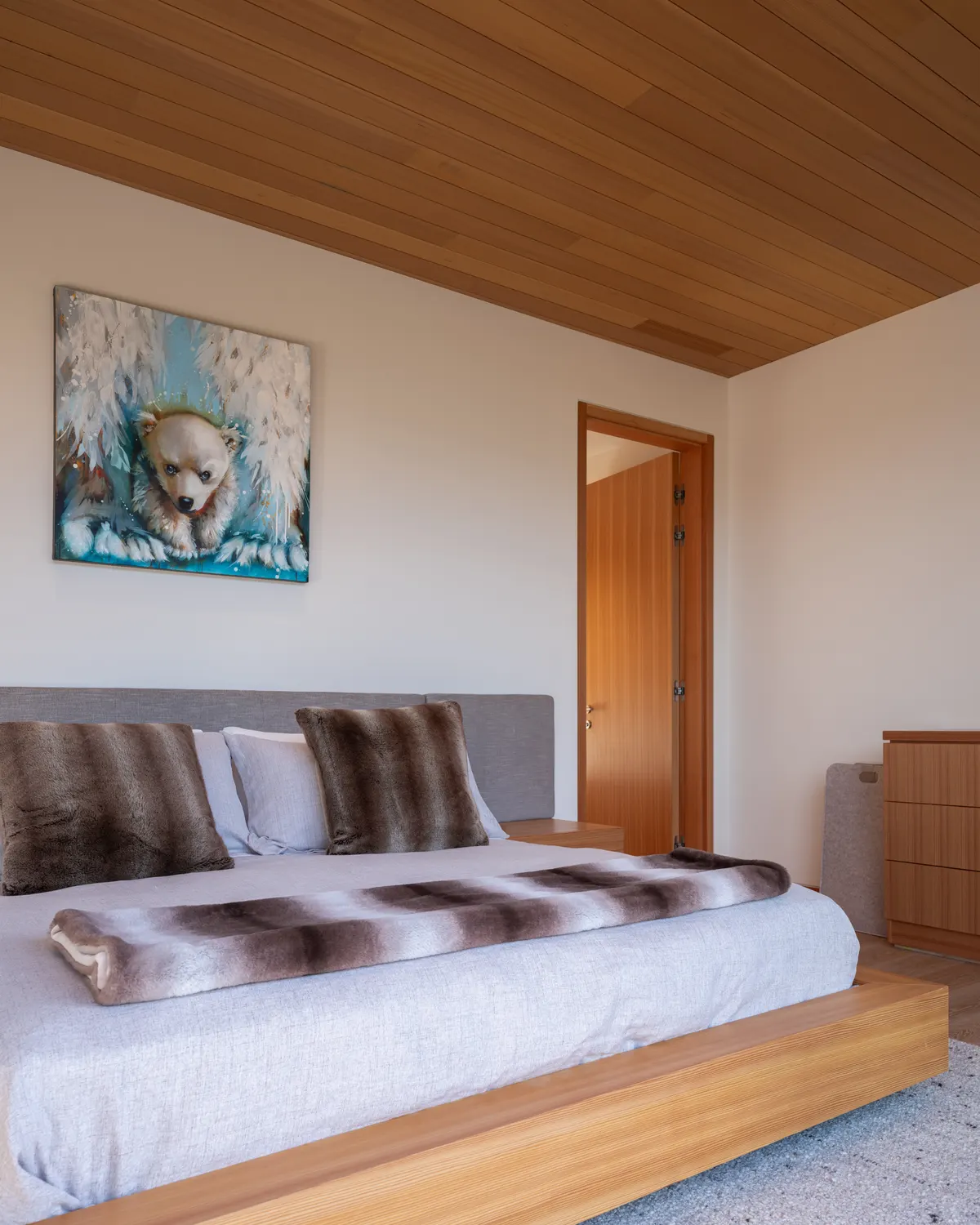 A bed under a wood ceiling, a painting above it, Panorama Ridge, Whistler
