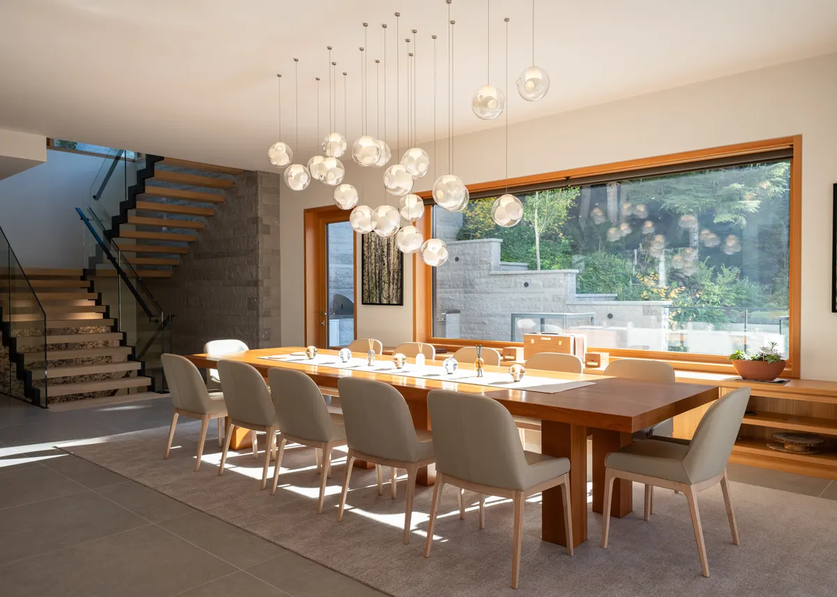 The dining table under a cluster of glass pendants, windows to the trees, Panorama Ridge, Whistler