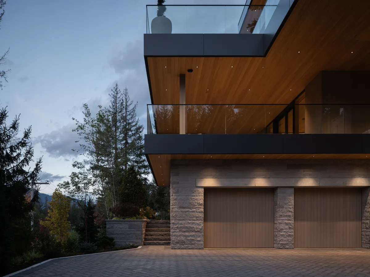 The garage elevation at dusk, two wood doors in the stone base, Panorama Ridge, Whistler