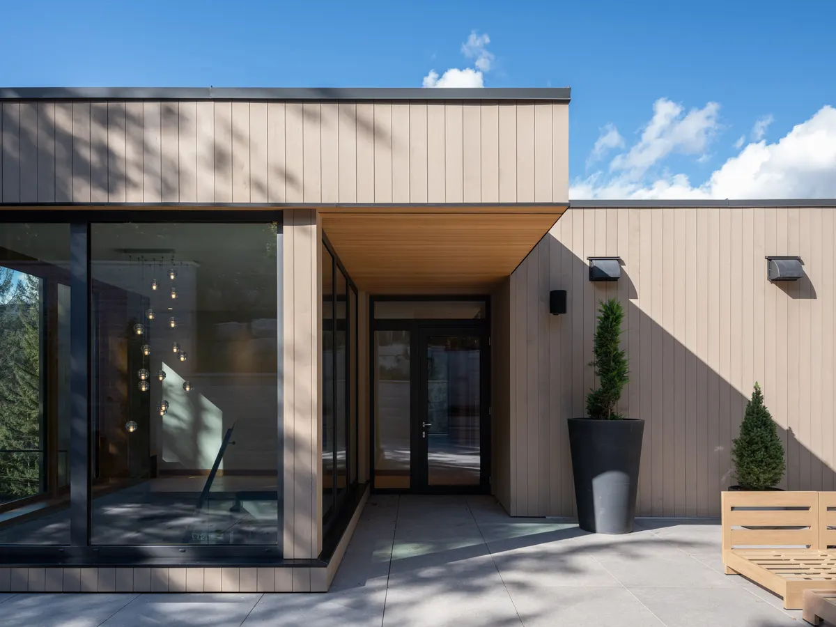 The entry elevation, pale wood cladding, glass, and a wood door, Panorama Ridge, Whistler