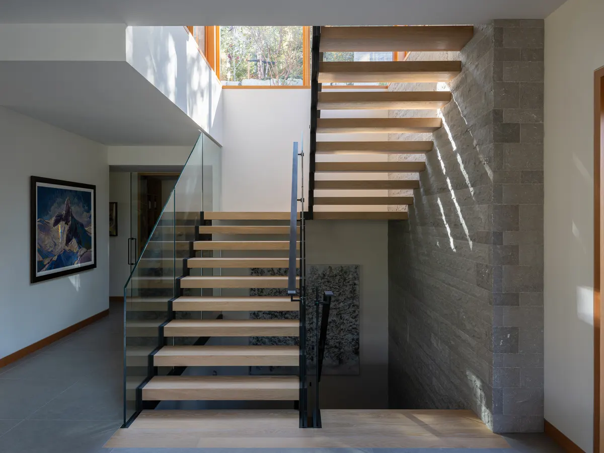 An interior stair, a glass guard and a stone pier, daylight from above, Panorama Ridge, Whistler