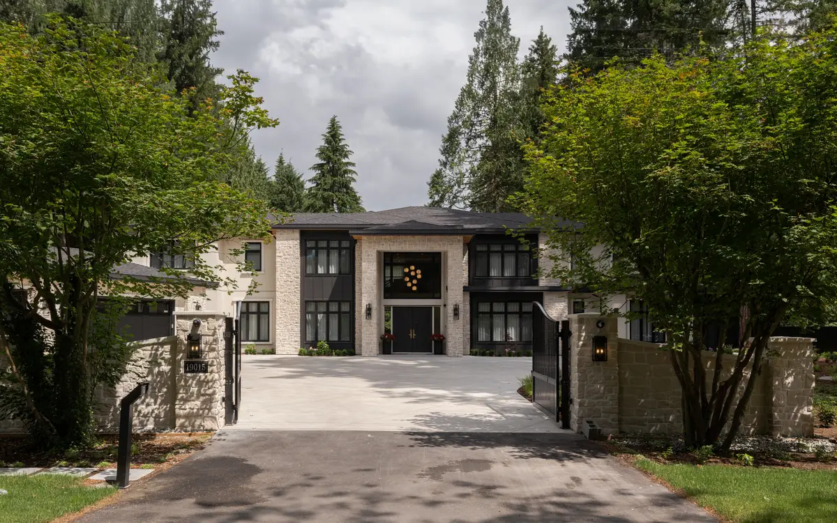 The drive up to the house, stone and black windows under the trees