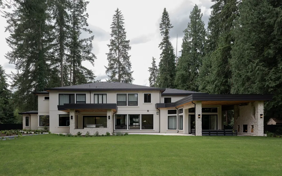 The front of the house across the lawn, forest behind