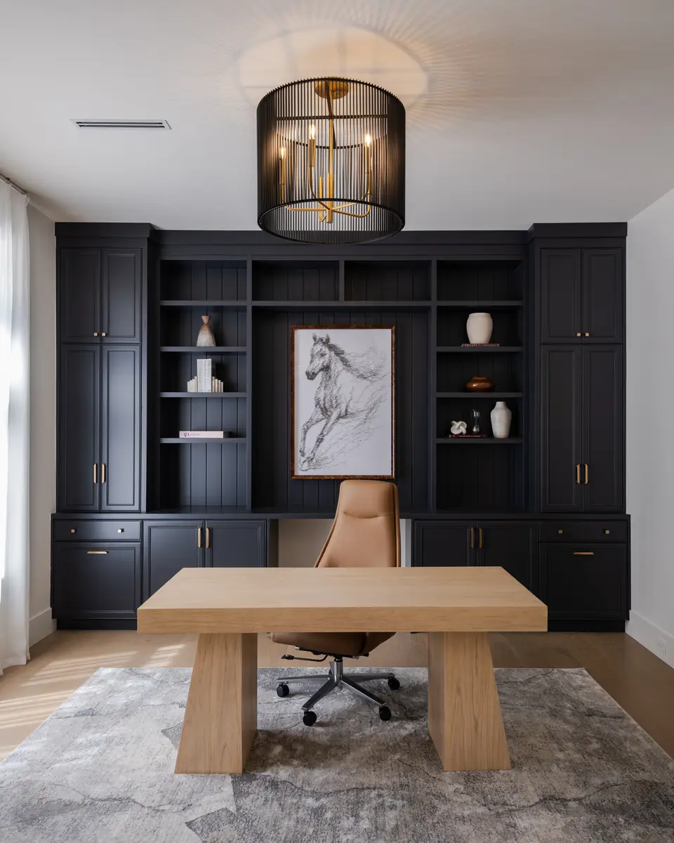 An office with black built-in shelves and a wood desk