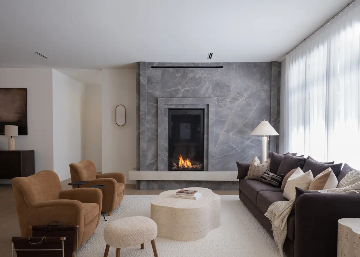 The living room, a grey stone fireplace and sofas by the windows