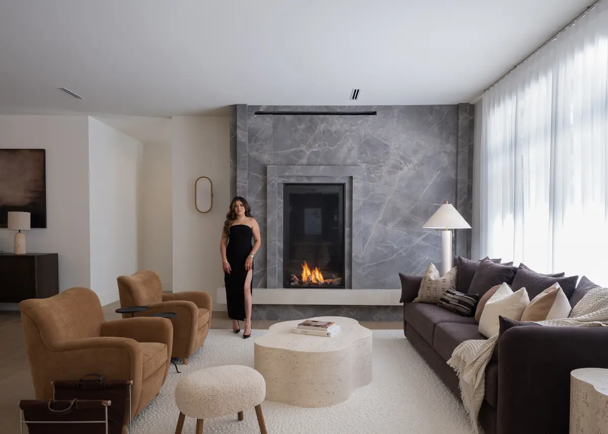The living room wide, fireplace, sofas, and a wall of windows
