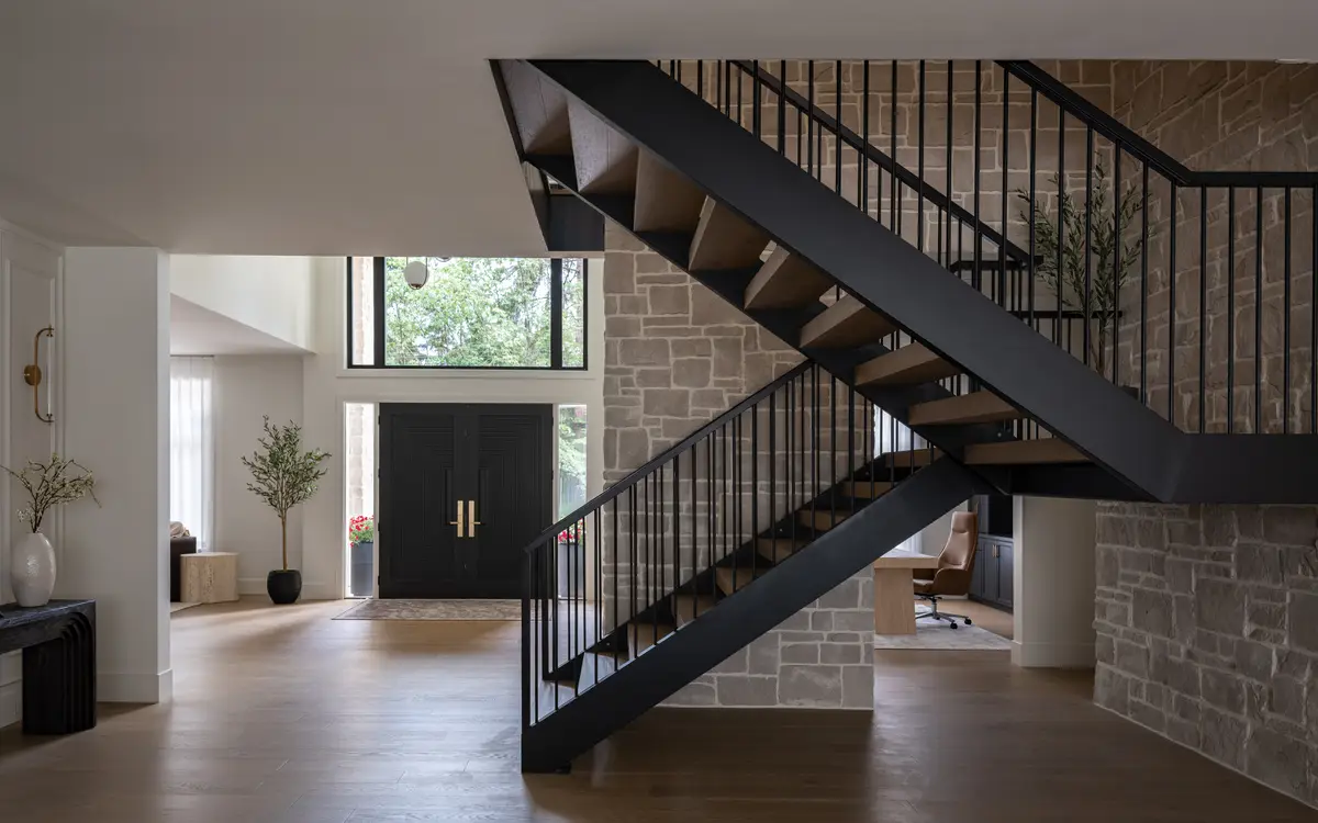 An open stair against a stone wall, the front door beyond
