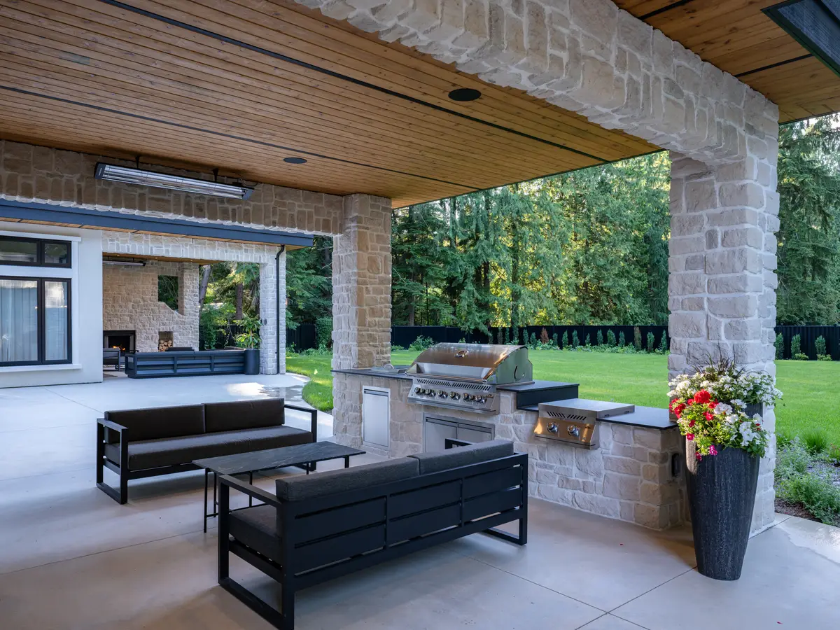 Outdoor sofas under the covered patio, a grill set into the stone counter