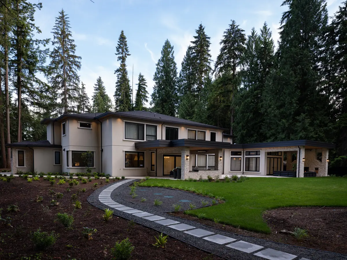 The house at dusk, a curved path through the garden, forest behind