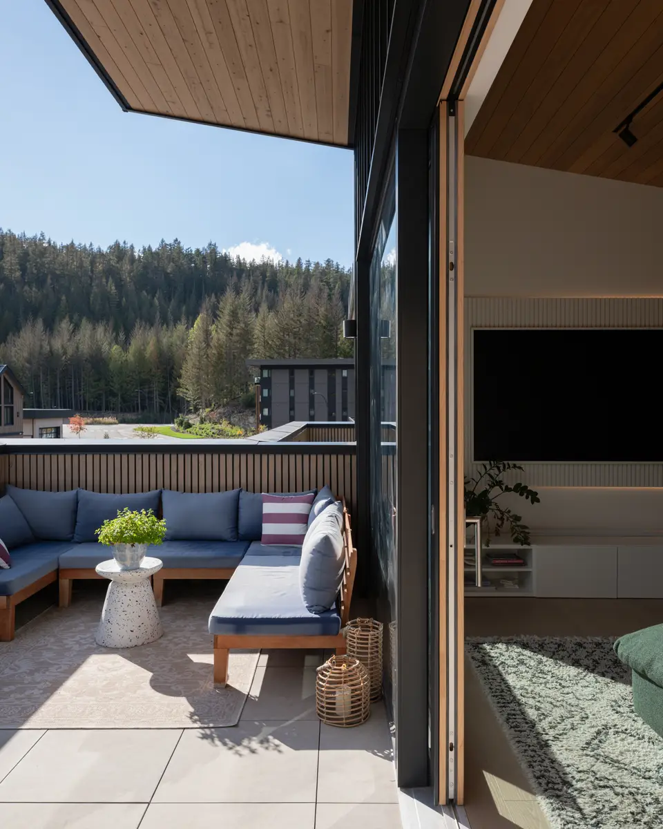 Covered deck with a blue sectional and the forest beyond at Riverrun Place, Whistler
