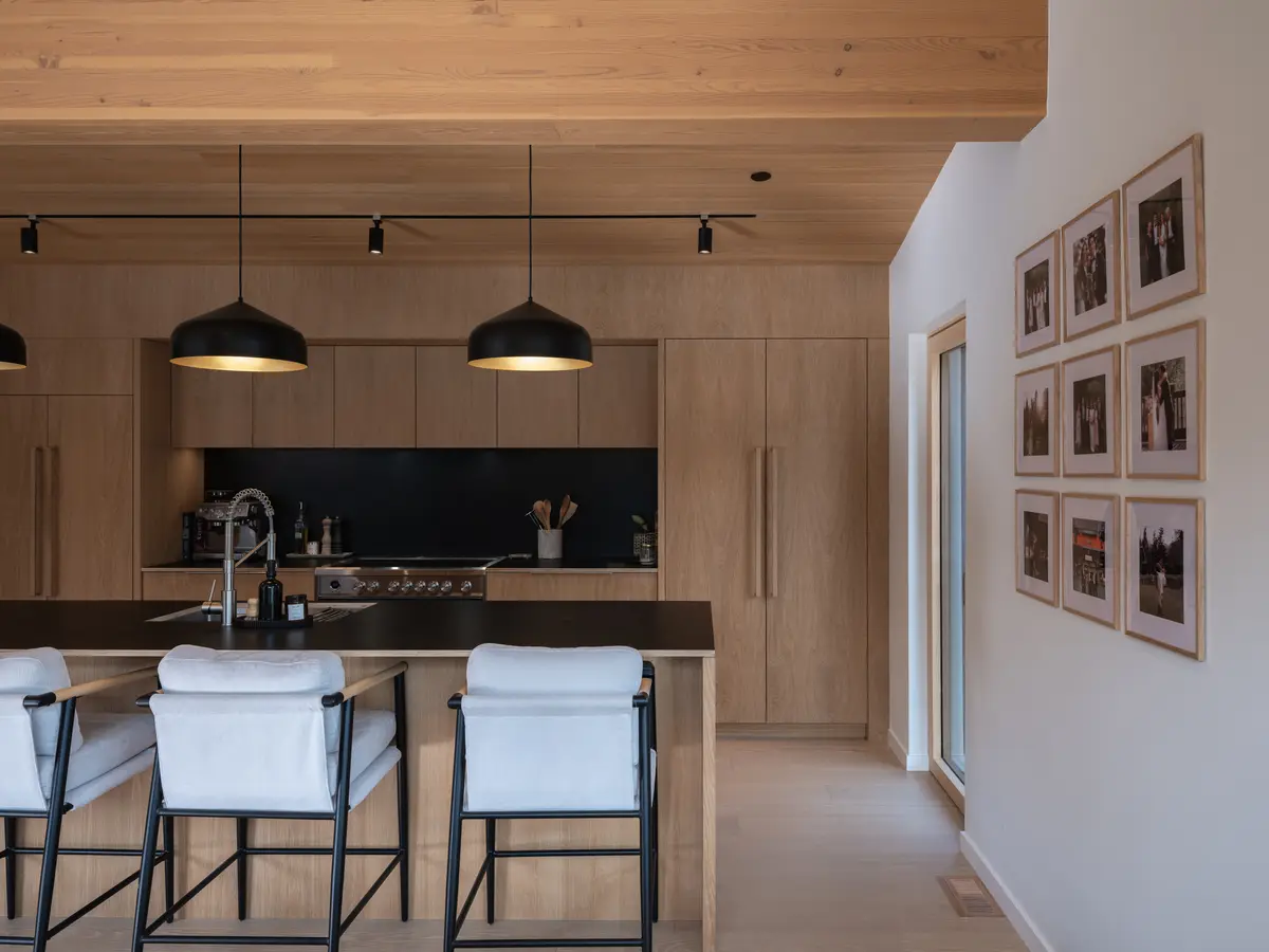 Kitchen with wood millwork, a dark island, and black pendants at Riverrun Place, Whistler