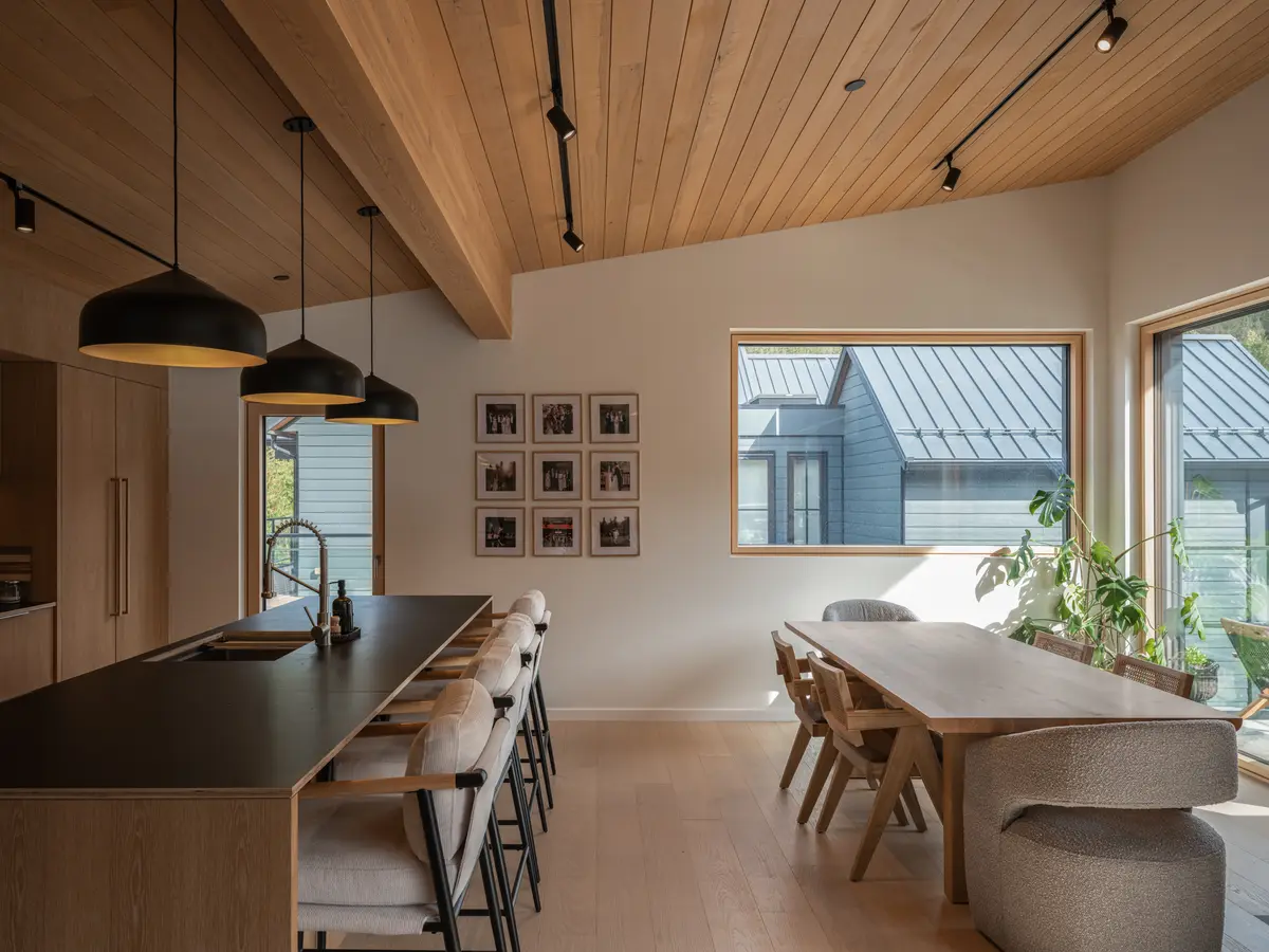 Kitchen island and dining table under a wood ceiling at Riverrun Place, Whistler