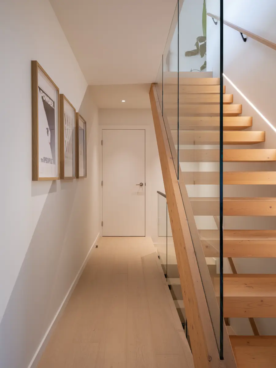 Stair hall with a wood stair and a glass guard at Riverrun Place, Whistler