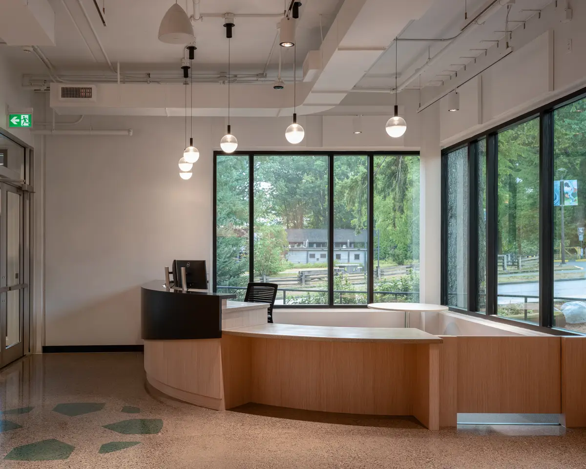 A curved wood reception desk in front of a window wall
