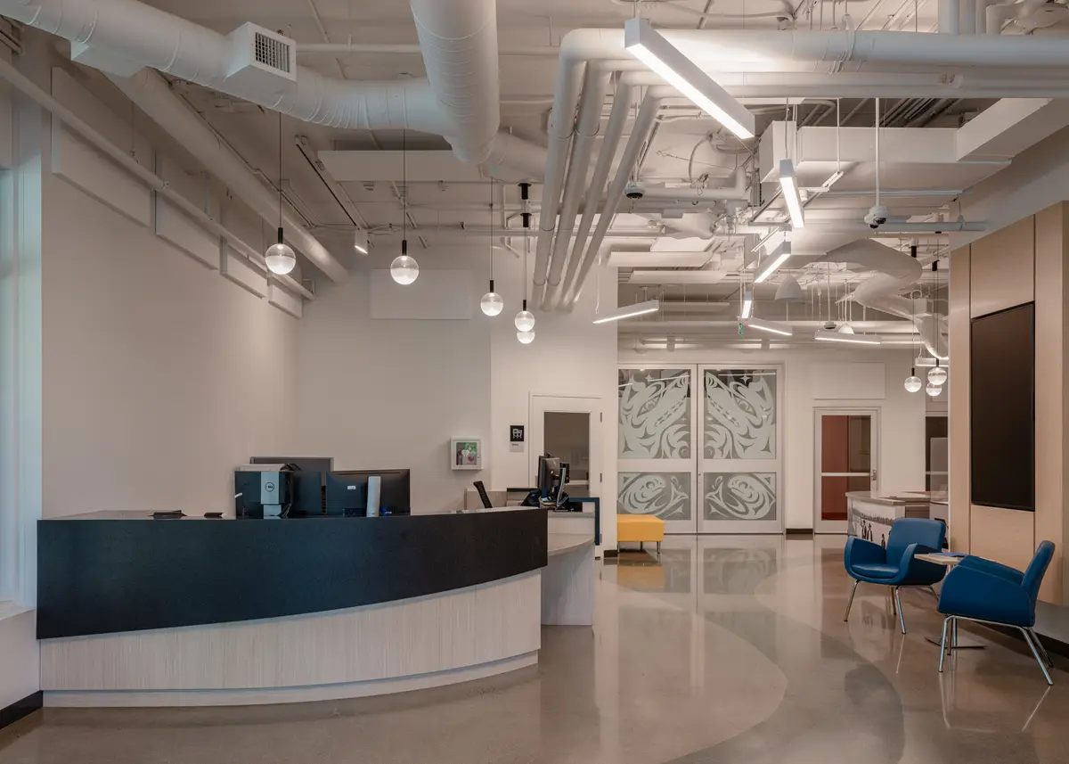 The reception desk, blue chairs, and doors behind