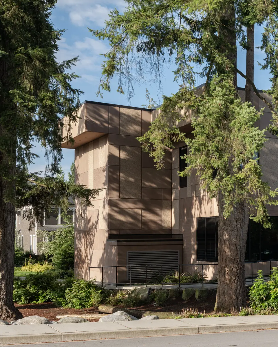 The building through tall trees, glazing at the ground floor