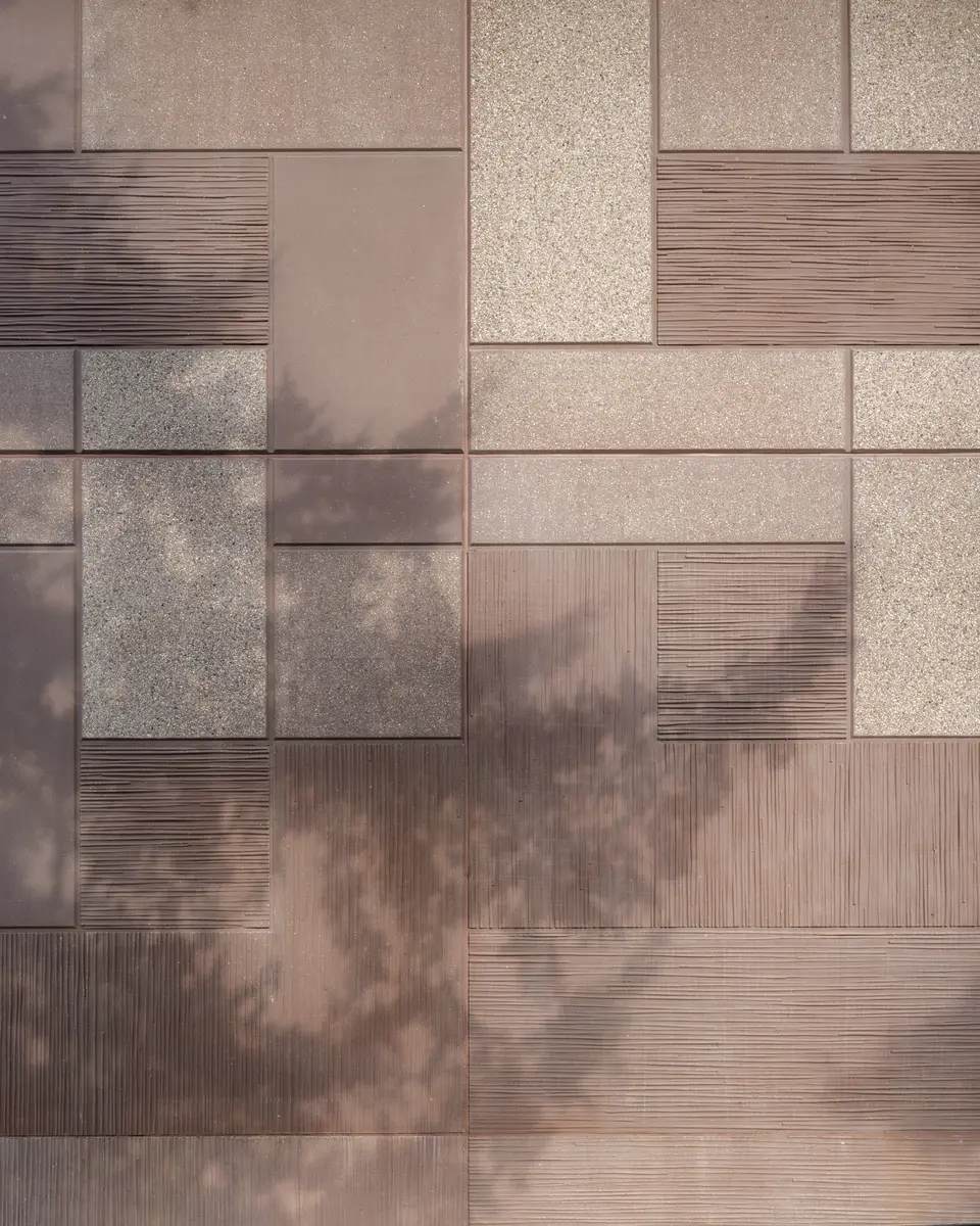A close view of the large wall panels, leaf shadows across them
