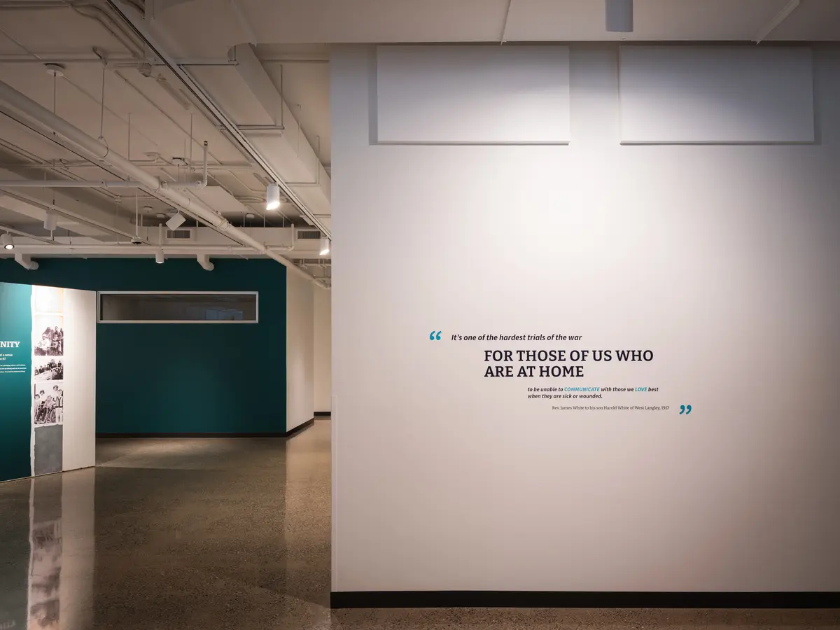 A white exhibition wall with a short line of text, teal panels beside it