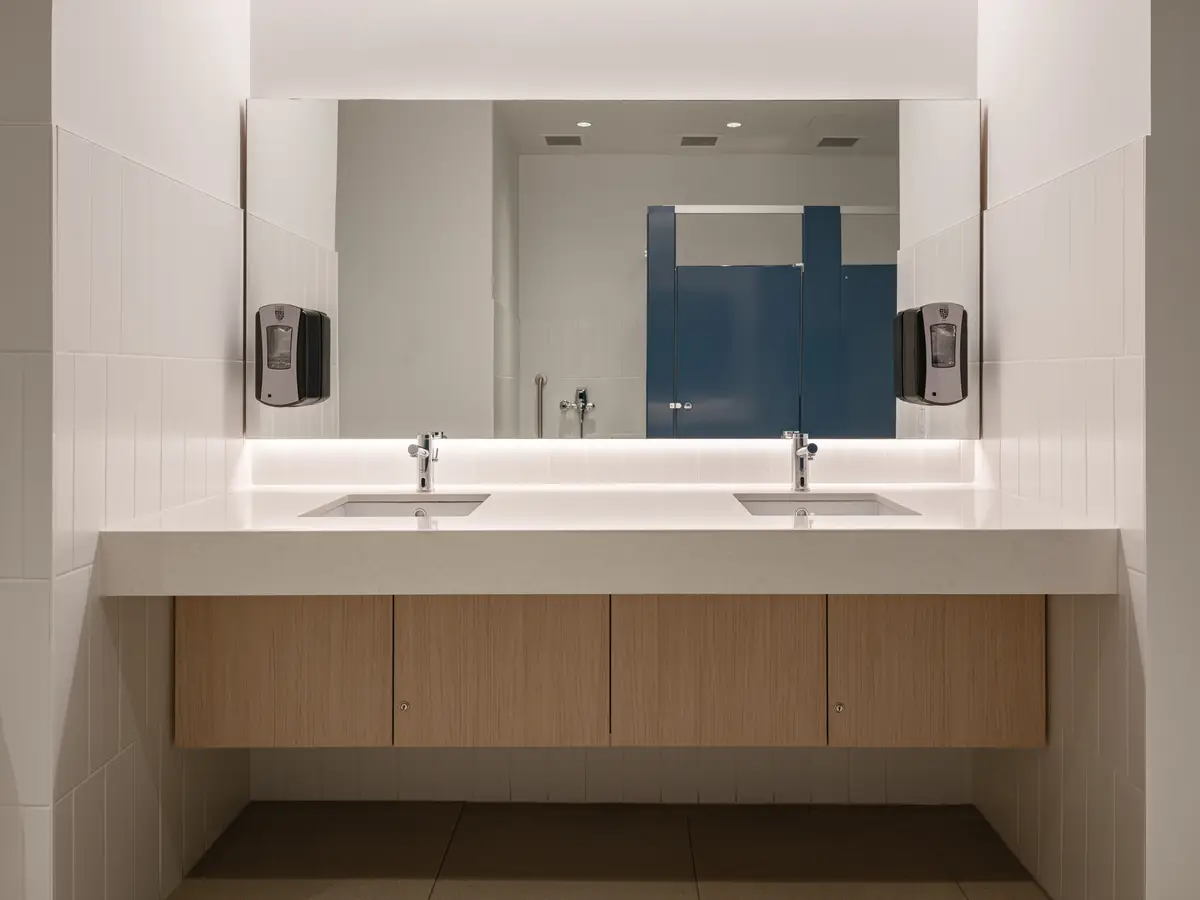 A washroom vanity in wood, two sinks and a mirror