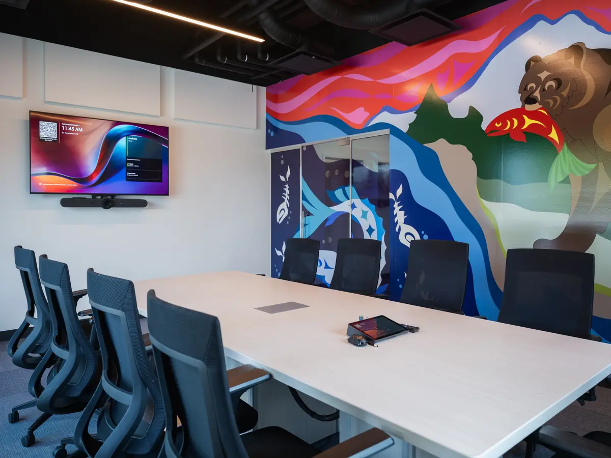 A meeting room, a mural of a bear on the wall and a long table
