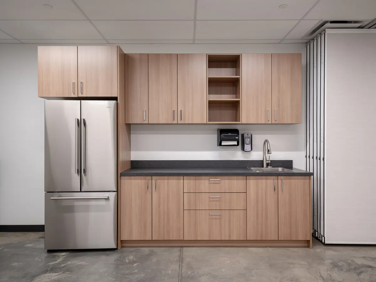 A kitchenette with wood cabinets and a refrigerator