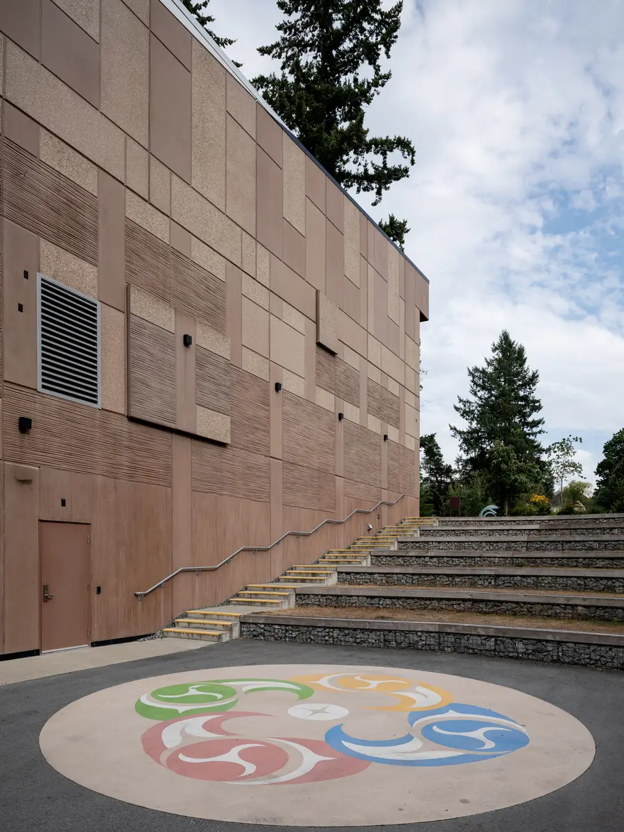 Steps up to a wood-clad wall, a painted circle in the paving