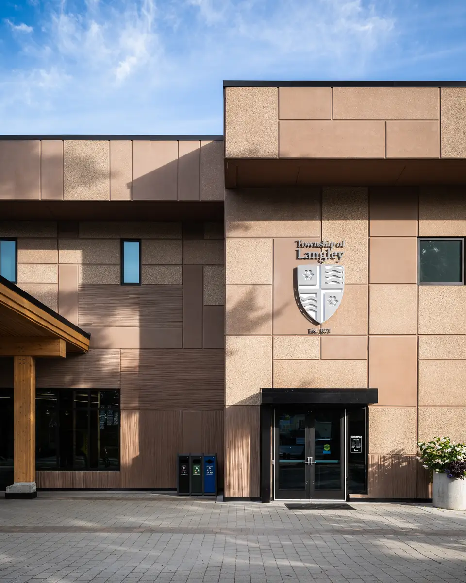 The entry doors under the canopy, the Township of Langley crest on the wall