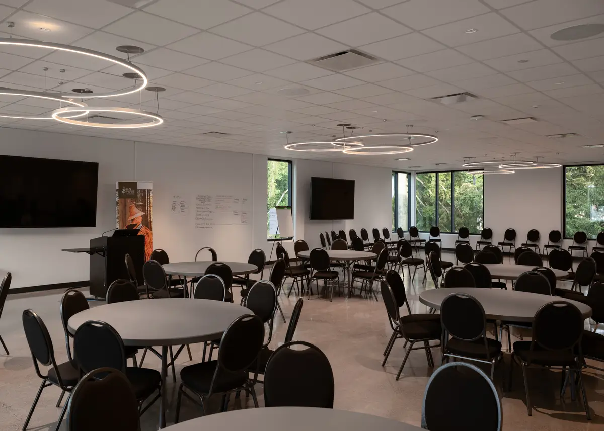 A room of round tables and chairs, windows along one wall