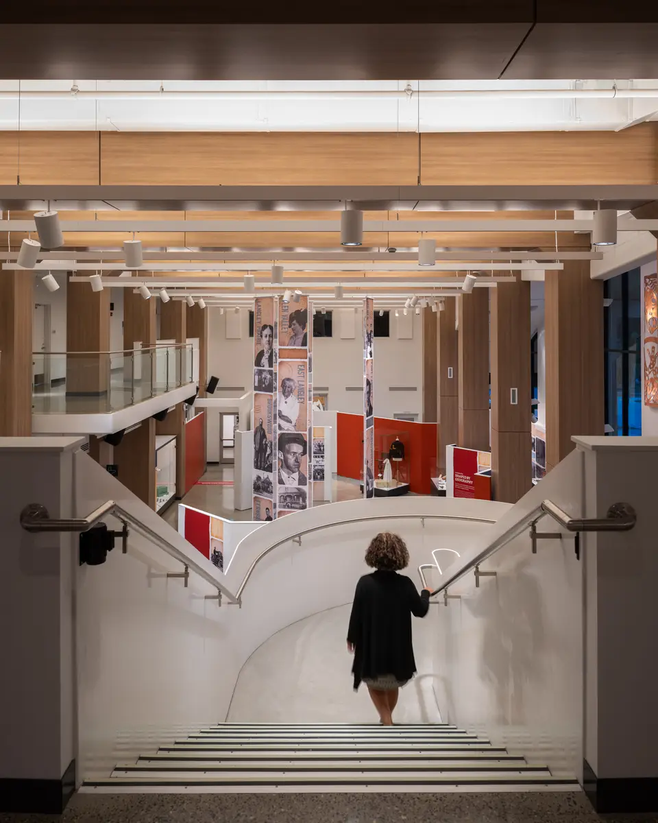 The stair hall, a person on the lower flight, bridges above
