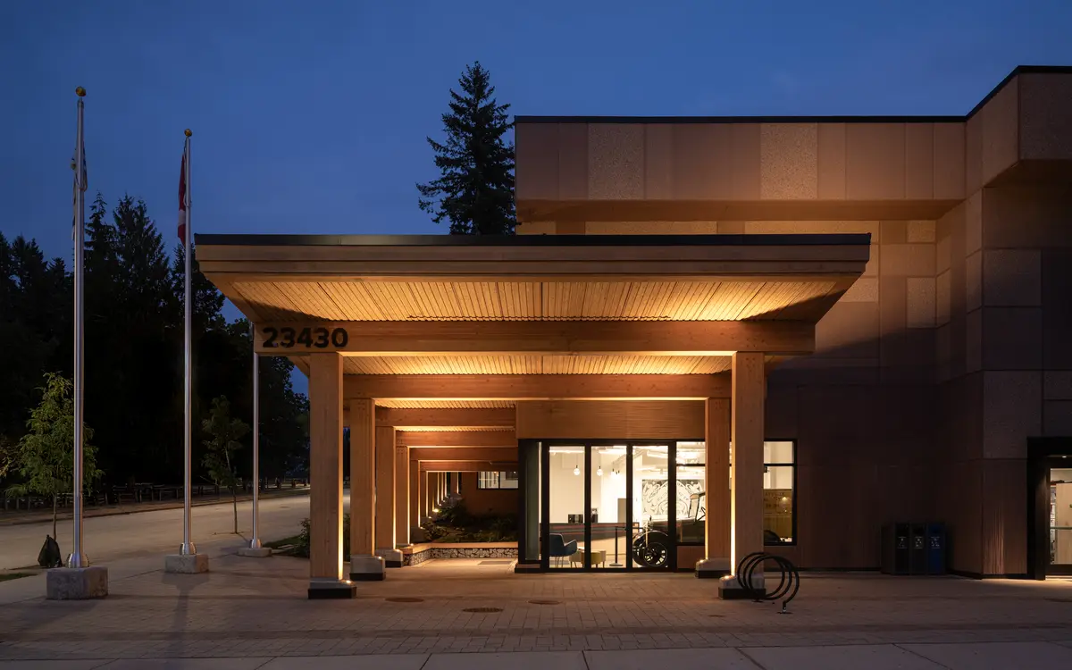 The entry at dusk, light pouring from under the canopy