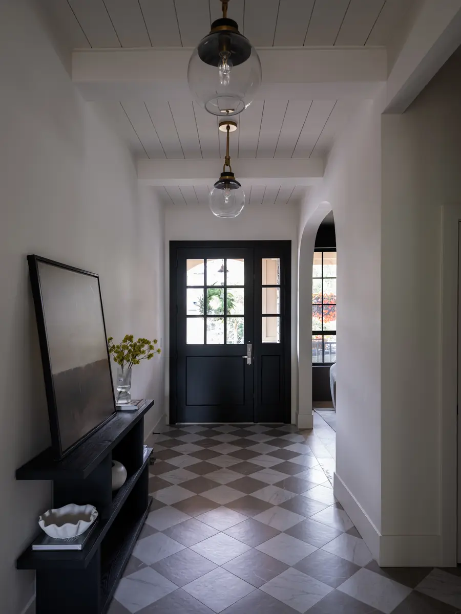 A checkerboard floor, a console, and black double doors