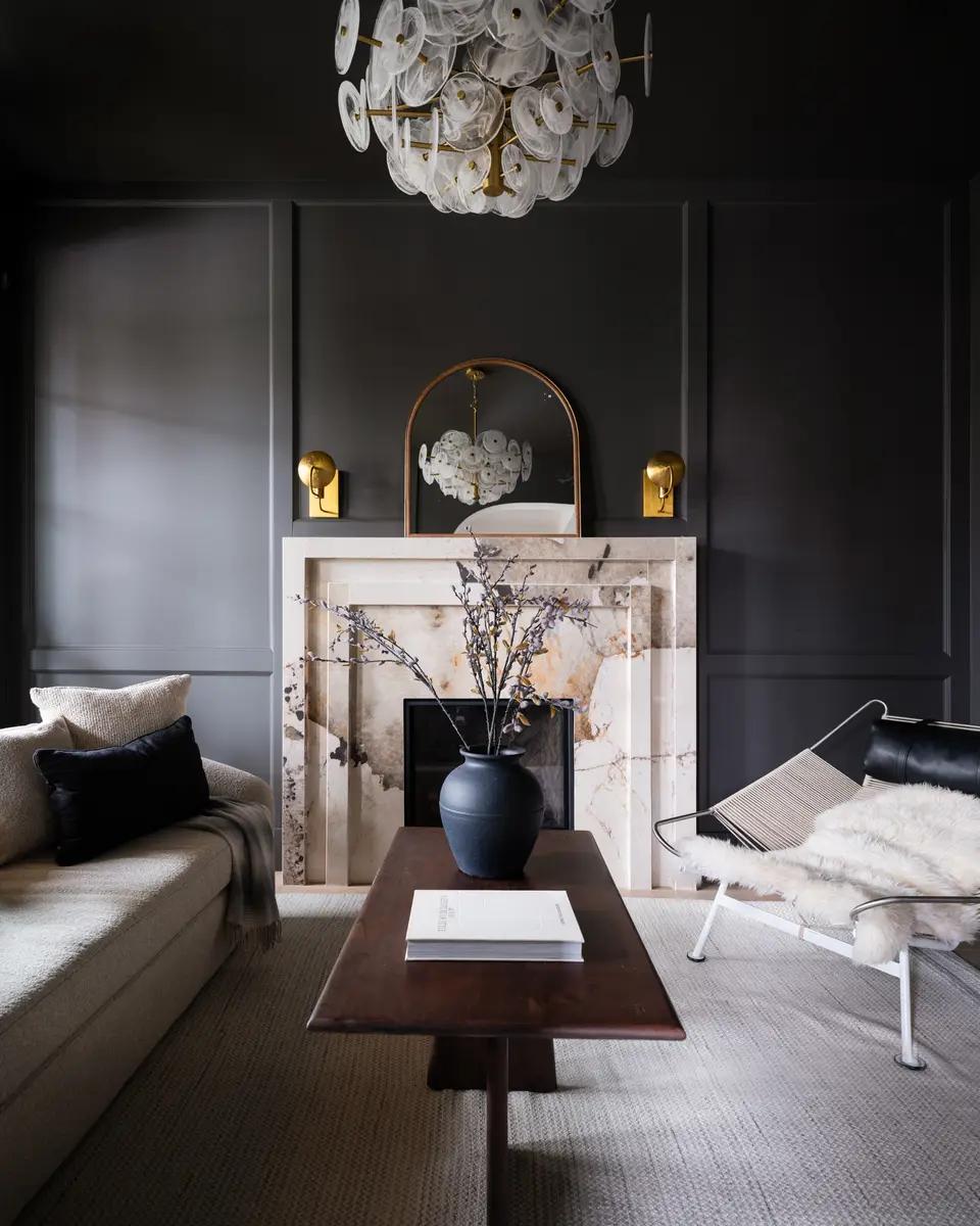 The sitting room fireplace, dark paneling and a chandelier